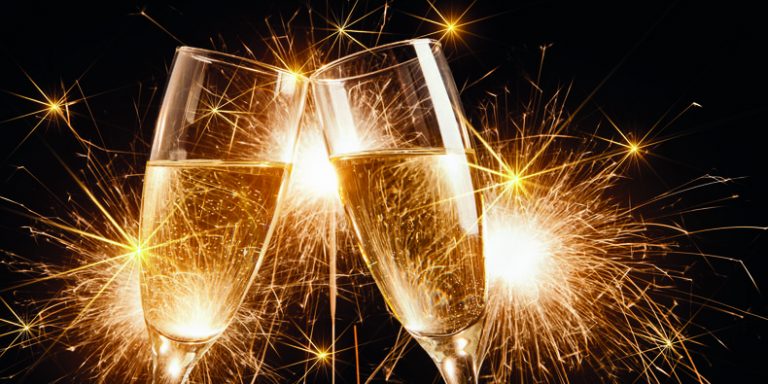 Glasses of champagne and sparklers on bright background with sparklers